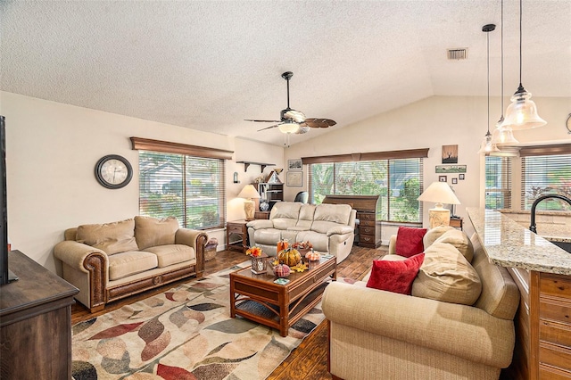 living room featuring ceiling fan, hardwood / wood-style flooring, vaulted ceiling, and a healthy amount of sunlight