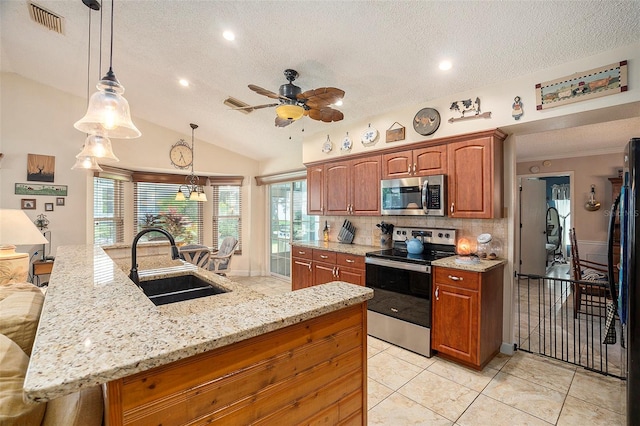 kitchen featuring lofted ceiling, sink, appliances with stainless steel finishes, decorative light fixtures, and a textured ceiling