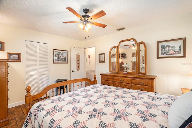 bedroom with ceiling fan, dark wood-type flooring, a closet, and a textured ceiling