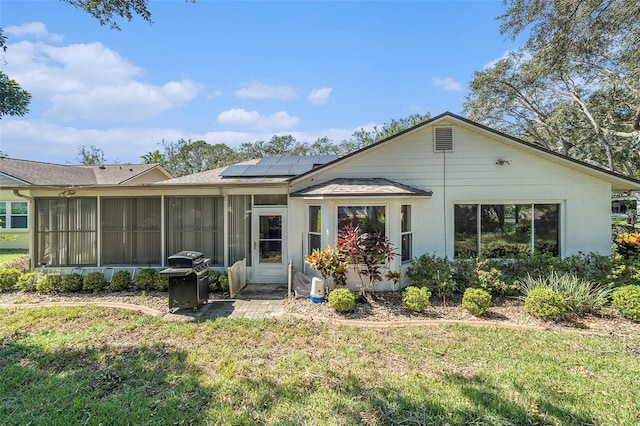 rear view of house featuring a yard, solar panels, and a sunroom