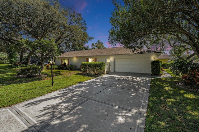 ranch-style house with a garage and a lawn