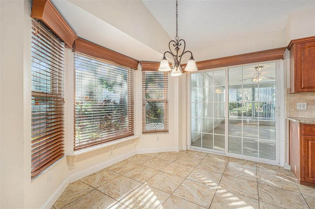 unfurnished dining area featuring lofted ceiling, a healthy amount of sunlight, and ceiling fan with notable chandelier