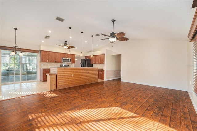 kitchen featuring hanging light fixtures, light wood-type flooring, a kitchen island, and black fridge