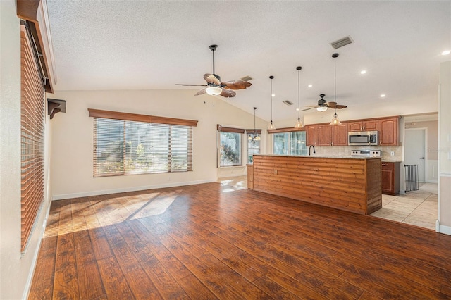 kitchen with stainless steel appliances, lofted ceiling, light hardwood / wood-style floors, pendant lighting, and a kitchen island