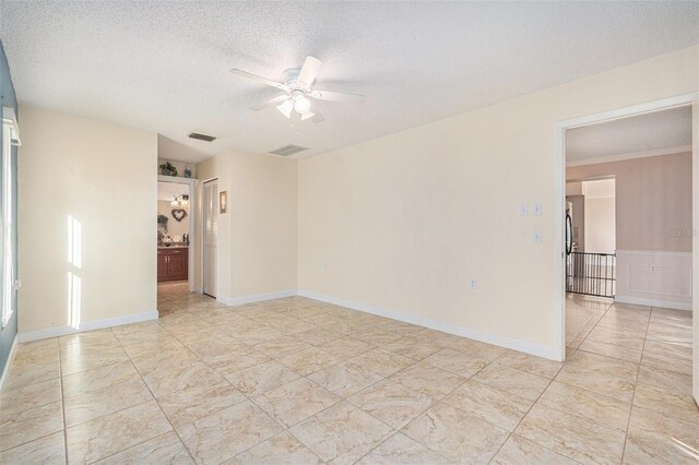 empty room with ceiling fan, crown molding, and a textured ceiling