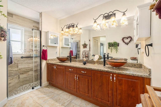 bathroom with vanity, a shower with door, and a textured ceiling