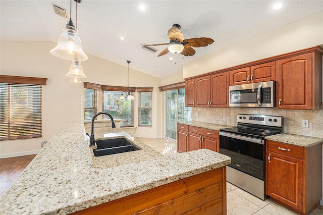 kitchen with decorative light fixtures, sink, vaulted ceiling, tasteful backsplash, and appliances with stainless steel finishes