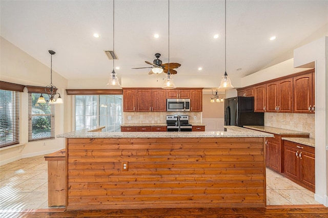 kitchen with appliances with stainless steel finishes, vaulted ceiling, light tile patterned floors, hanging light fixtures, and light stone countertops