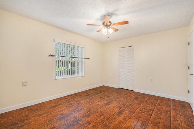 empty room with ceiling fan, dark hardwood / wood-style flooring, and a textured ceiling