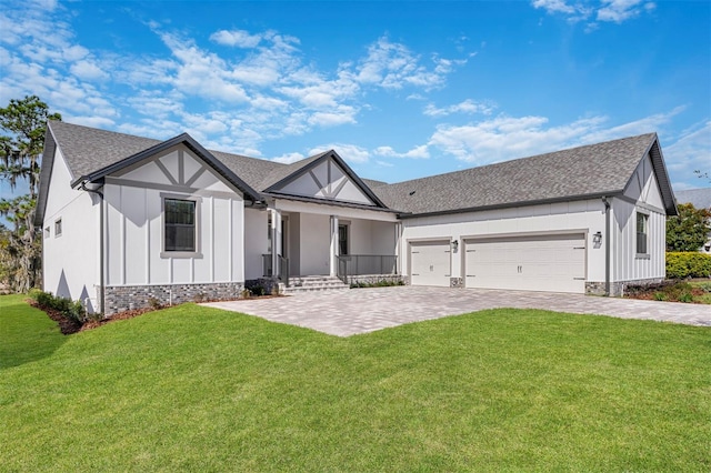view of front of house featuring board and batten siding, decorative driveway, a porch, a front yard, and a garage