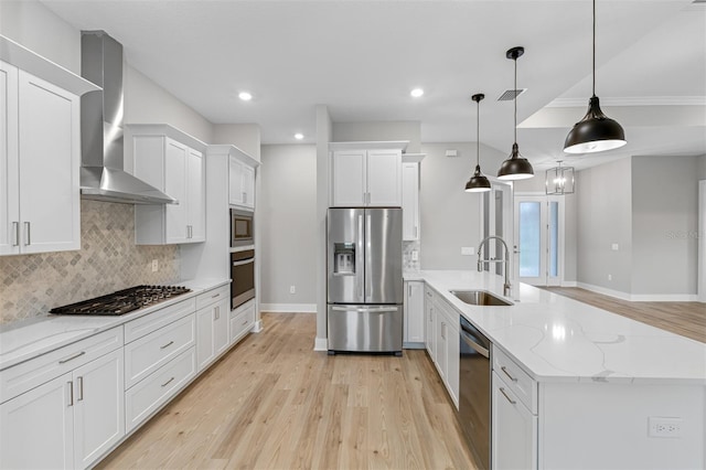 kitchen featuring wall chimney exhaust hood, light hardwood / wood-style flooring, decorative light fixtures, stainless steel appliances, and white cabinets