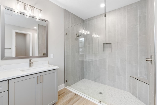 bathroom featuring baseboards, recessed lighting, wood finished floors, a shower stall, and vanity
