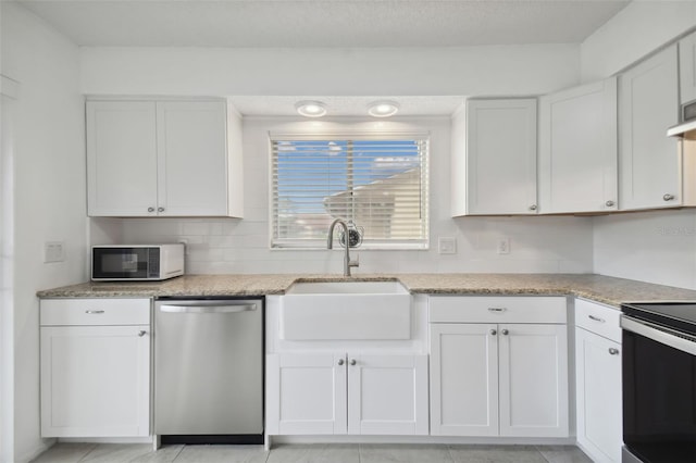 kitchen featuring light tile patterned flooring, white cabinets, stainless steel appliances, and sink