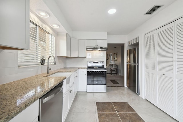 kitchen featuring decorative backsplash, appliances with stainless steel finishes, white cabinetry, sink, and light stone counters