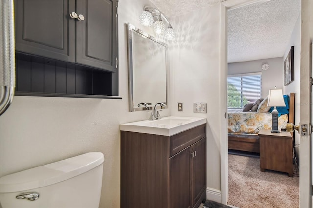 bathroom featuring toilet, a textured ceiling, and vanity