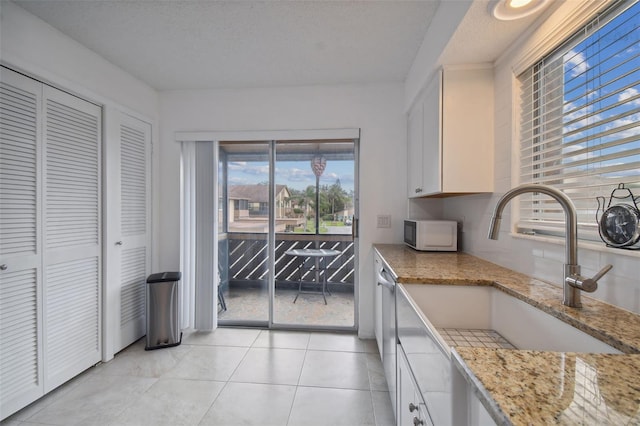 4028 Davit Dr Unit 4028, New Port Richey, FL 34652 - kitchen featuring white microwave, a sink, white cabinets, light tile patterned floors, and light stone counters