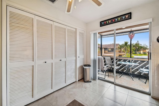 doorway featuring light tile patterned floors and ceiling fan