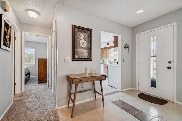 foyer entrance with a textured ceiling and light tile patterned floors