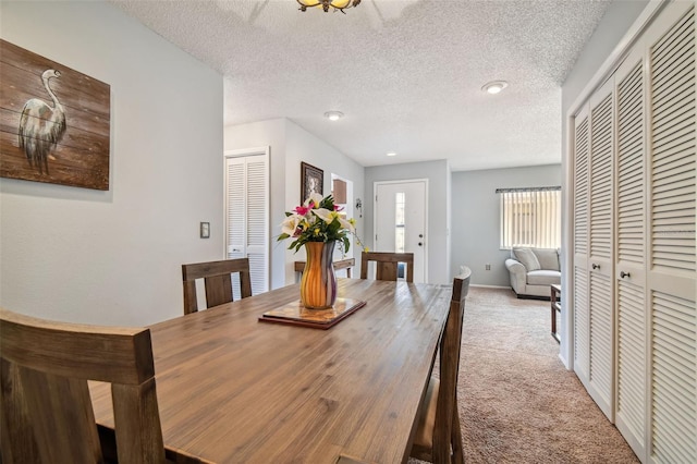 carpeted dining space with a textured ceiling