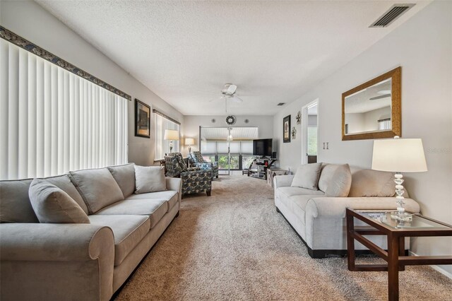 living room featuring a textured ceiling, carpet floors, and ceiling fan