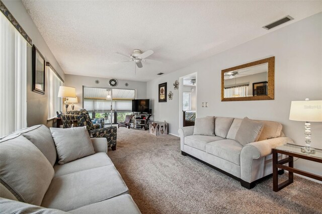 living room with carpet floors, a textured ceiling, and ceiling fan