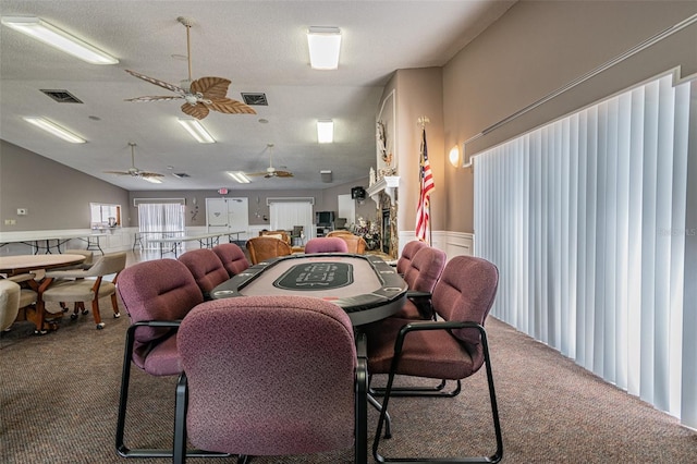 carpeted dining area featuring a fireplace, a textured ceiling, and ceiling fan