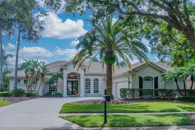 view of front of house with french doors, a garage, and a front lawn