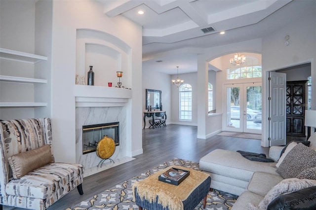 living room with french doors, coffered ceiling, dark hardwood / wood-style flooring, a notable chandelier, and a high end fireplace