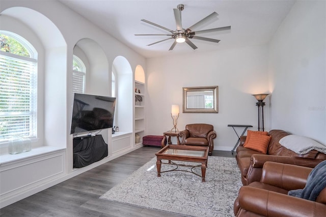 living room featuring dark wood-type flooring, built in features, and ceiling fan