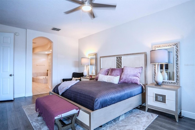 bedroom with ceiling fan, connected bathroom, and dark hardwood / wood-style flooring