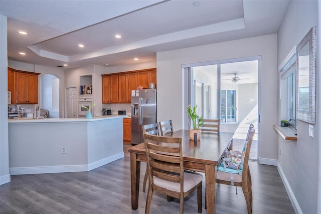 dining area featuring dark hardwood / wood-style floors, sink, and a tray ceiling