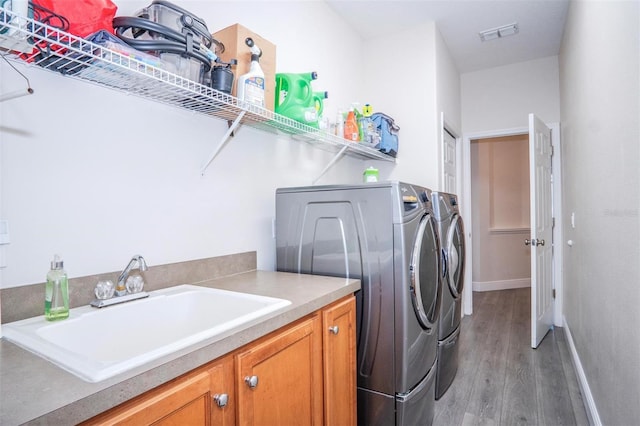 laundry room with cabinets, dark hardwood / wood-style flooring, sink, and washing machine and dryer