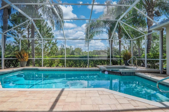 view of pool with an in ground hot tub, a patio area, and glass enclosure