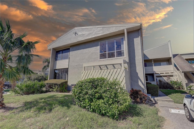 property exterior at dusk featuring a yard and a balcony