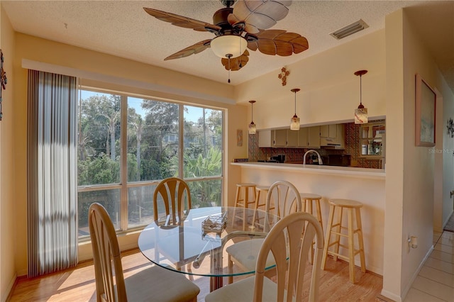 dining area featuring light hardwood / wood-style flooring, a textured ceiling, and ceiling fan