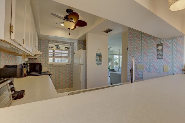 kitchen with white cabinetry, white fridge, and ceiling fan