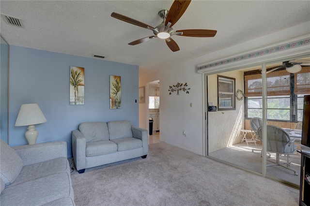 carpeted living room with a textured ceiling and ceiling fan