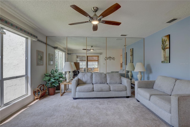 carpeted living room featuring a textured ceiling and ceiling fan