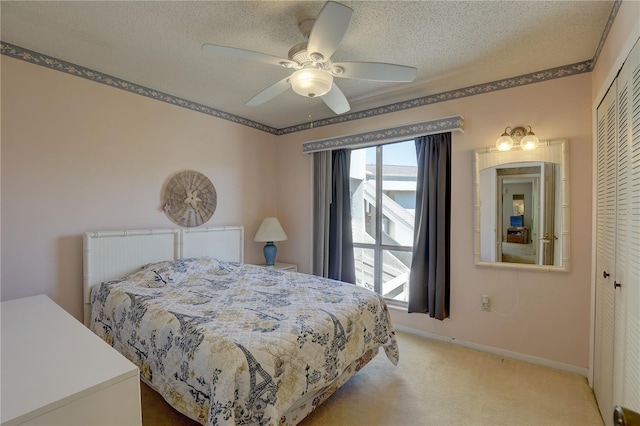 bedroom featuring a closet, ceiling fan, light carpet, and a textured ceiling