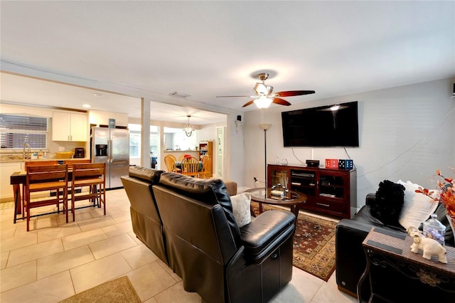 living room with light tile patterned flooring and ceiling fan with notable chandelier