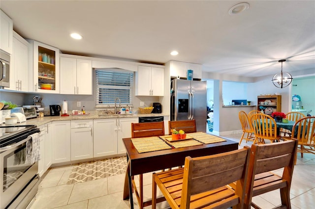 kitchen with light stone countertops, a notable chandelier, appliances with stainless steel finishes, and white cabinets