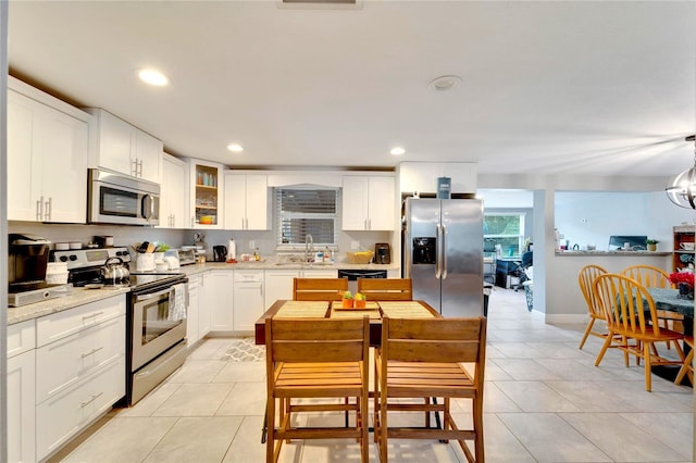 kitchen featuring sink, stainless steel appliances, white cabinets, light tile patterned floors, and an inviting chandelier