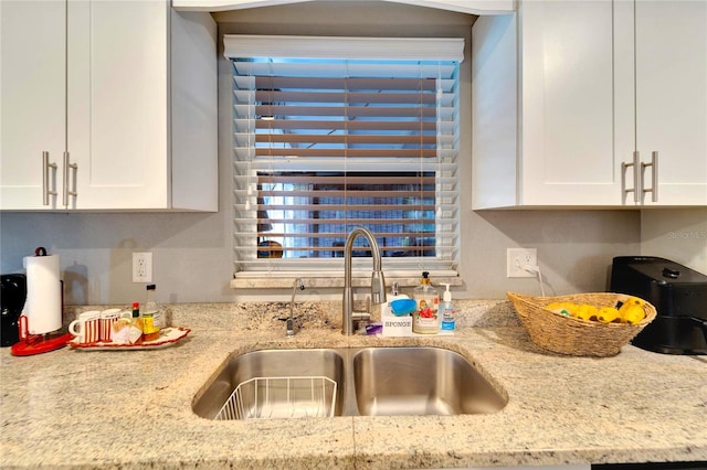 kitchen featuring white cabinets, light stone countertops, and sink