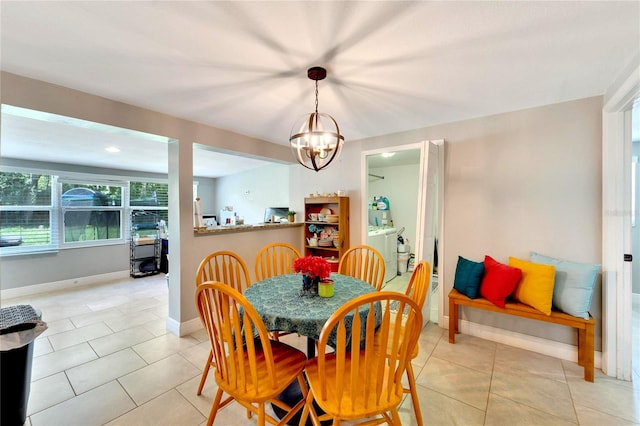 dining room featuring a notable chandelier, washing machine and dryer, and light tile patterned floors