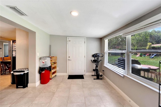 workout area with light tile patterned flooring and a textured ceiling