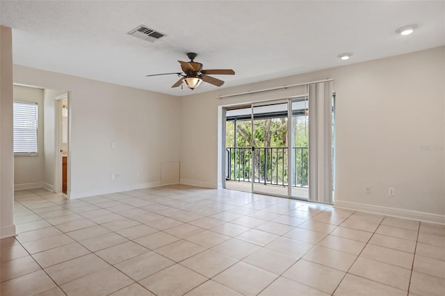 empty room featuring a textured ceiling, light tile patterned floors, and ceiling fan