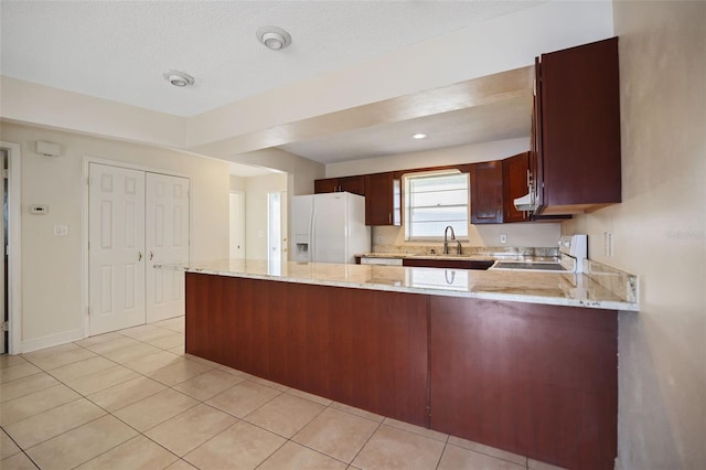 kitchen with stove, sink, kitchen peninsula, and white fridge with ice dispenser