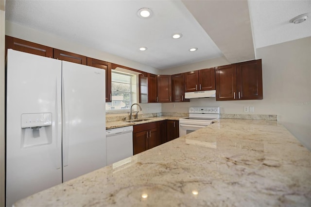 kitchen featuring white appliances, light stone countertops, and sink