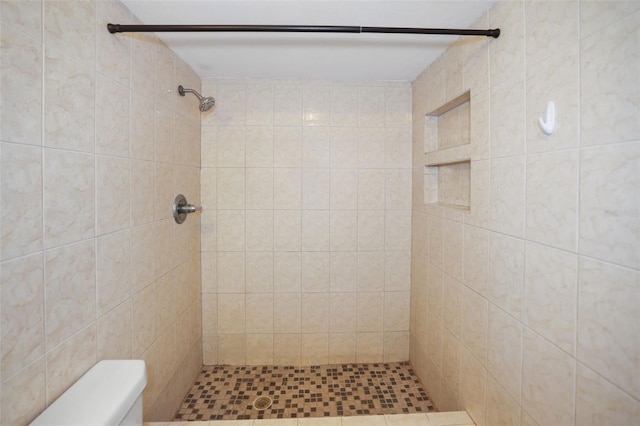 bathroom with a tile shower and toilet