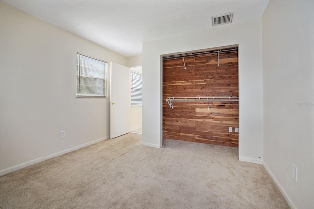 unfurnished bedroom featuring a closet, wood walls, and light colored carpet